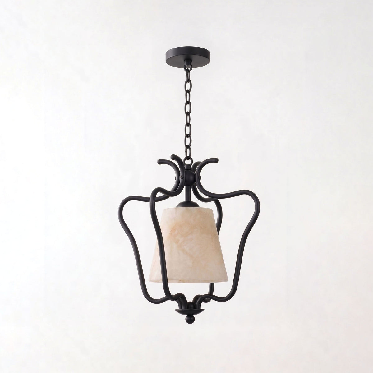 Set against a plain white background, the matte black finish of this Clérachic pendant scrolls into an open lantern frame.