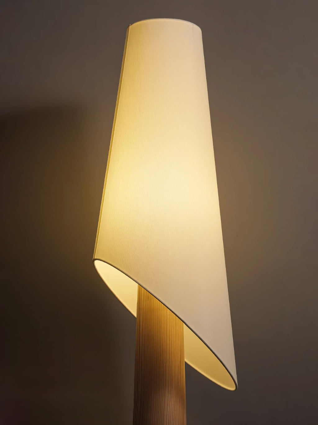 Close-up of the Clérachic floor lamp's angled fabric shade meeting its tapered wood-toned body.