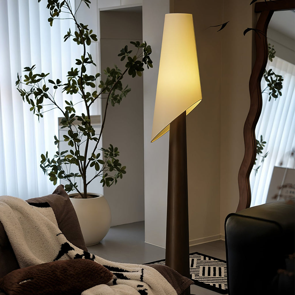 The walnut-toned Clérachic floor lamp glows beside a potted fig tree, with sheer curtains and a wall mirror.