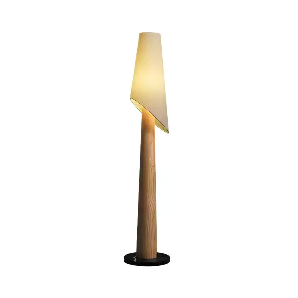 A walnut-toned Clérachic floor lamp stands lit against a plain white studio background, its cone-shaped body tapering down.