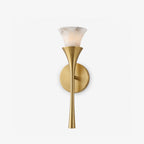 Studio shot on a bare white backdrop, this Clérachic sconce's tapered brass stem flares open to an alabaster shade.