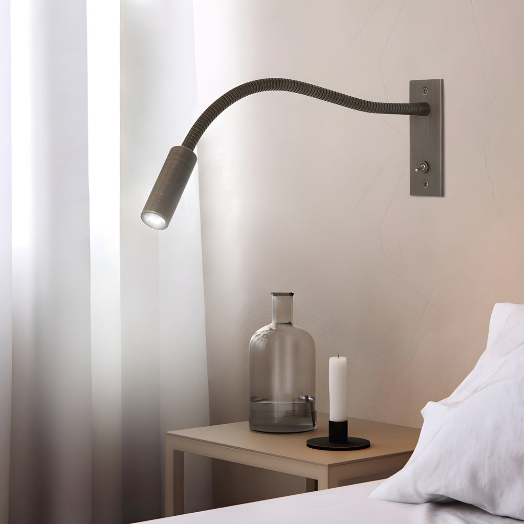 Sand nickel gooseneck wall lamp with arm bent toward a book