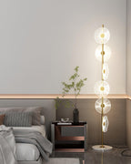 Near a striped cushion and a copper-trimmed nightstand holding a sprig of leaves, this Clérachic floor lamp lights the corner.