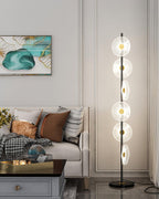 In a living room with a cream tufted sofa and teal print, this Clérachic floor lamp stands full-length beside a grey cabinet.