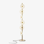 A second studio view of this Clérachic floor lamp against a plain grey backdrop, its acrylic discs lit along the gold pole.