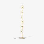 A near-identical studio shot of the lit Clérachic floor lamp, its cord curved slightly differently across the floor.