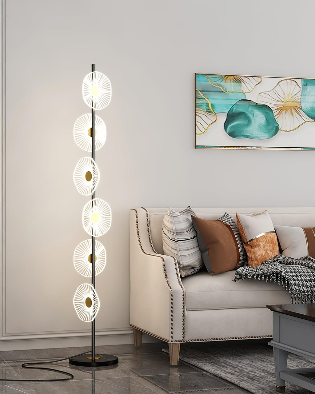 This Clérachic floor lamp stands on a dark round base beside a tufted sofa, its stacked acrylic discs glowing up the gold pole.