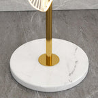 A macro detail shows this Clérachic floor lamp's gold pole meeting its round white marble base, veined in soft grey.