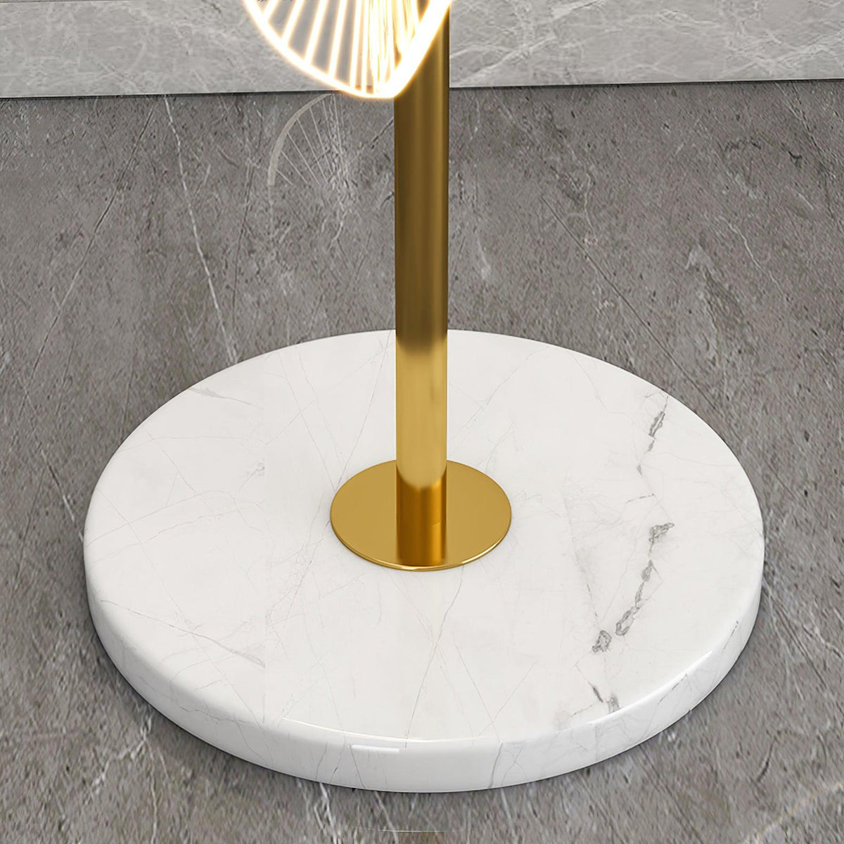 A macro detail shows this Clérachic floor lamp's gold pole meeting its round white marble base, veined in soft grey.