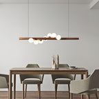Linear walnut pendant casting a warm even glow over a table