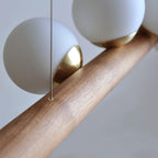 Warm glowing glass globes on a walnut bar against pale wall