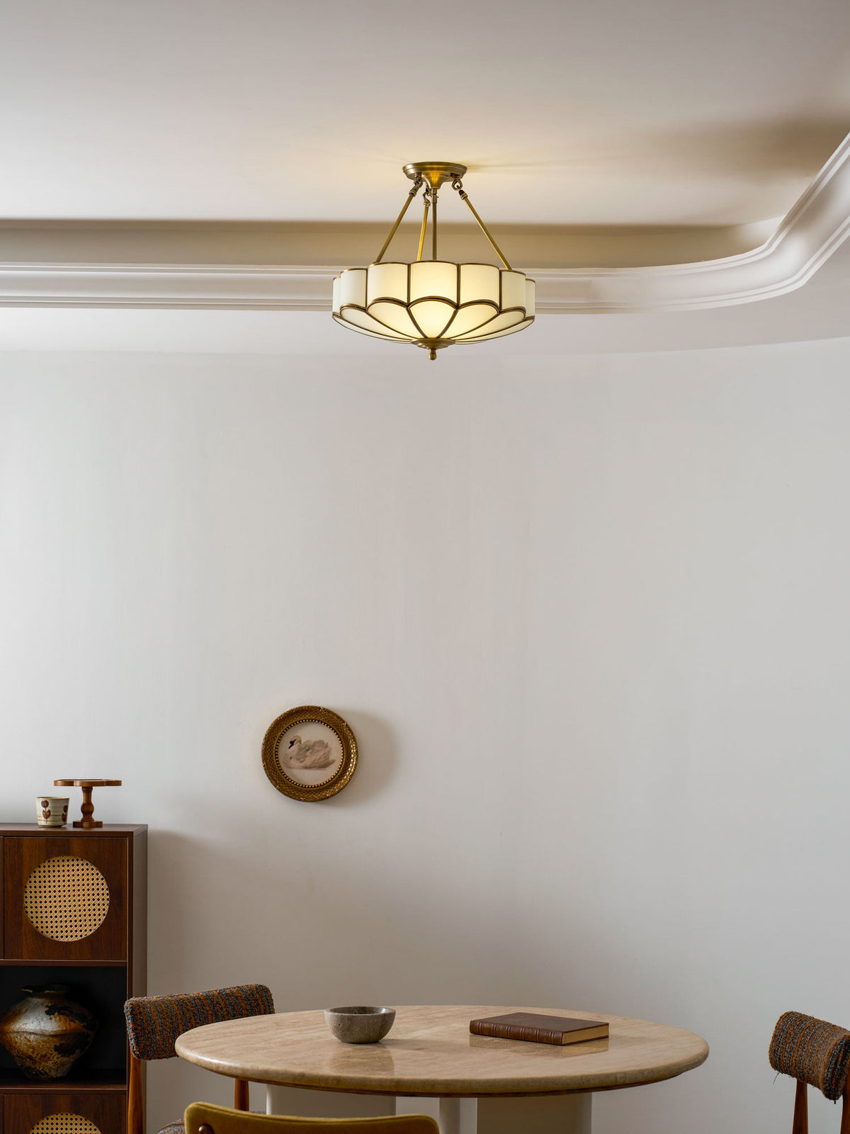 Close beneath the same crown moulding, this Clérachic ceiling light glows warm above a dining nook.
