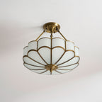 On a plain grey backdrop, this Clérachic ceiling light's brass-framed glass dome glows warm from a high angle.