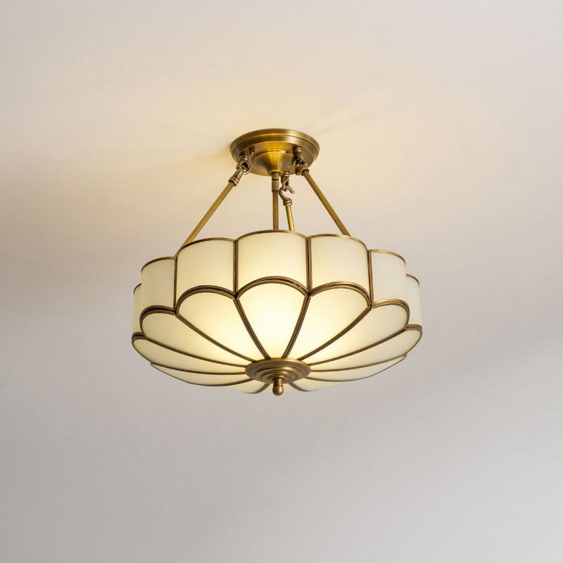 On a plain grey backdrop, this Clérachic ceiling light glows warm, seen from directly below its scalloped glass dome.