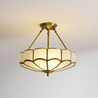 On a plain grey backdrop, this Clérachic ceiling light glows warm at a low angle, showing its hanging brass rods.