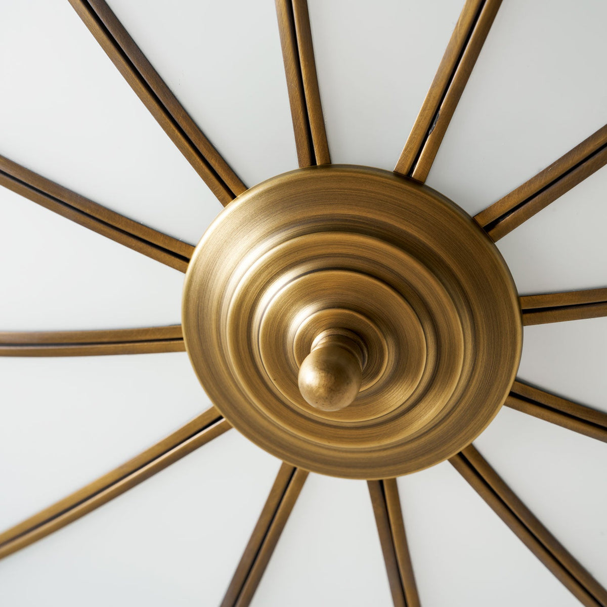 A close view of the same bare brass spoke frame beside this Clérachic ceiling light, its arms fanning out with no glass attached.