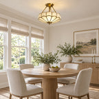 Above a round wood dining table with woven roman shades nearby, this Clérachic ceiling light glows warm in the room.