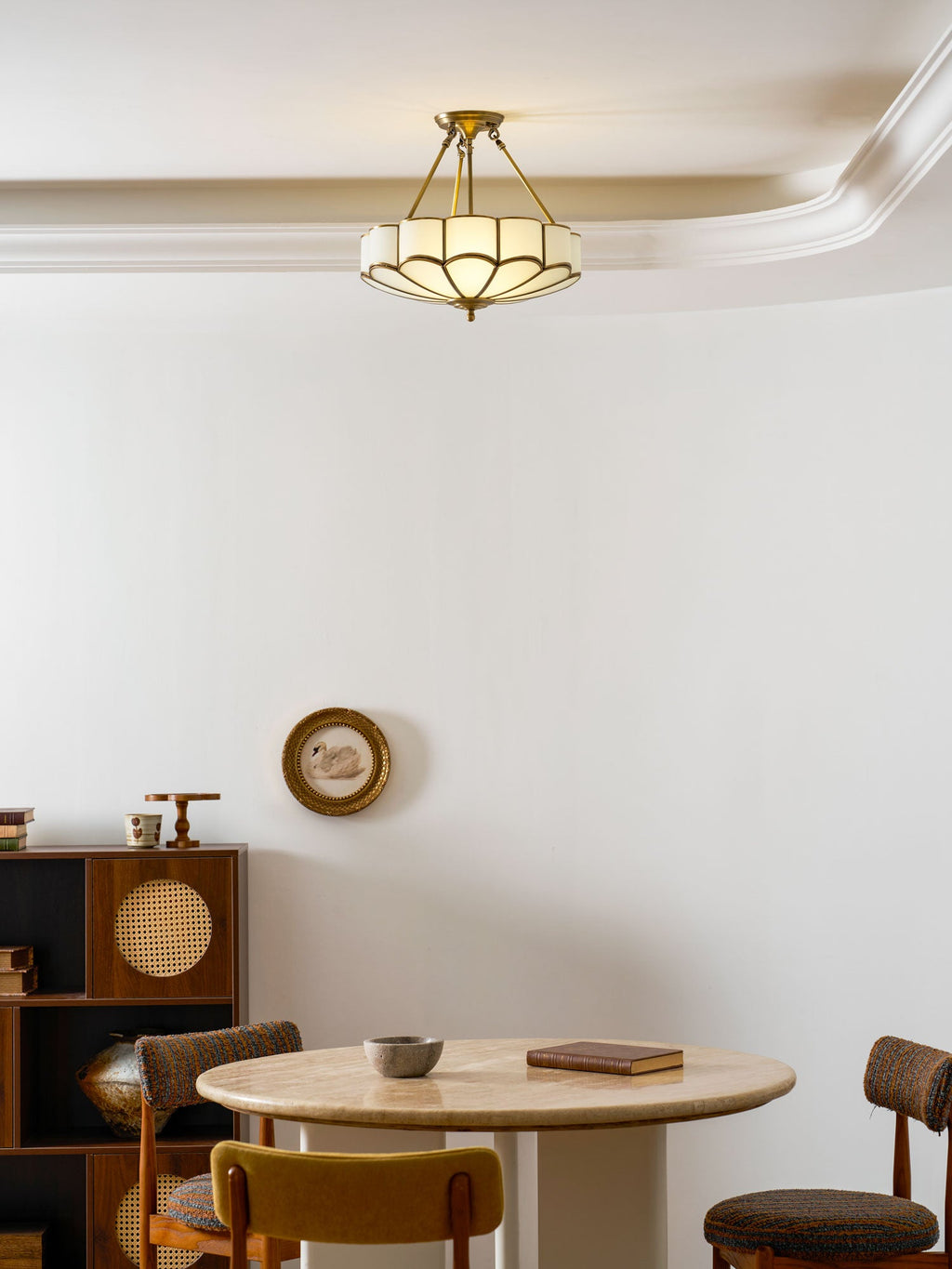 In a room with a round travertine table and a small wall mirror, this Clérachic ceiling light glows near the ceiling.