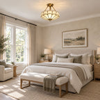 Above a neutral bed with a woven bench at its foot, this Clérachic ceiling light glows warm in a sunlit bedroom.
