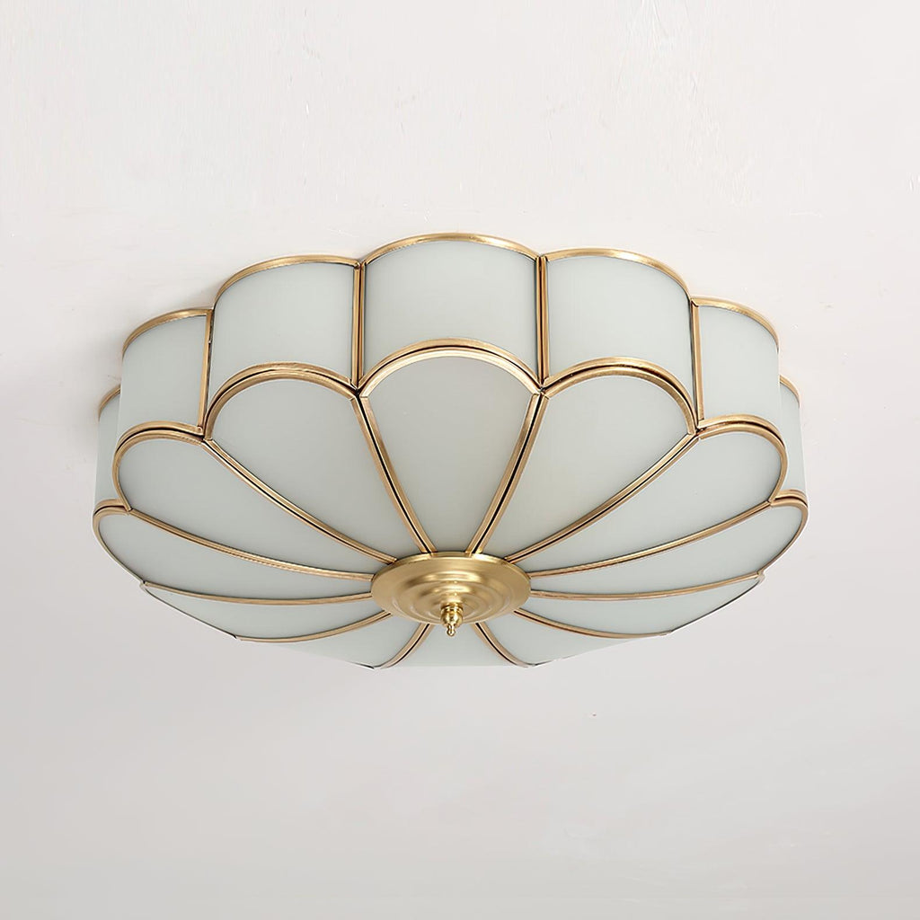 Frosted glass petal ceiling light with brass frame glowing softly