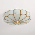 Frosted glass petal ceiling light with brass frame glowing softly
