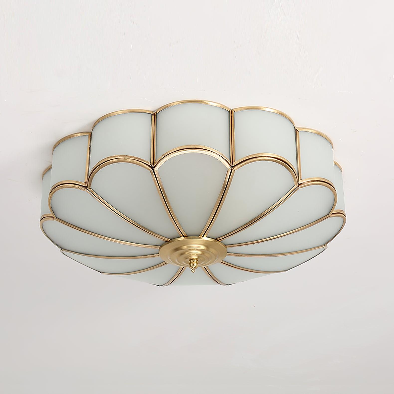 Frosted glass petal ceiling light with brass frame glowing softly
