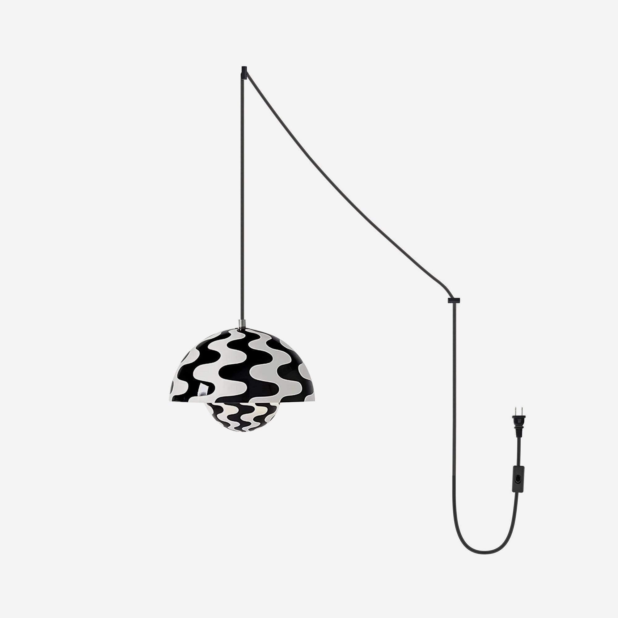 Monochrome wave-print pendant lit on a pale grey backdrop, cord swagged to a plug and switch