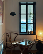 The same green pendant lit in the evening, glowing softly beside a window with the blinds down