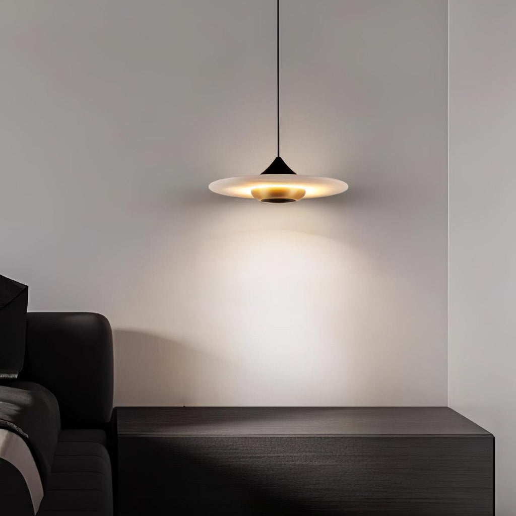 Clérachic white disc pendant hangs over a dark wood nightstand beside a leather headboard in a dim bedroom.