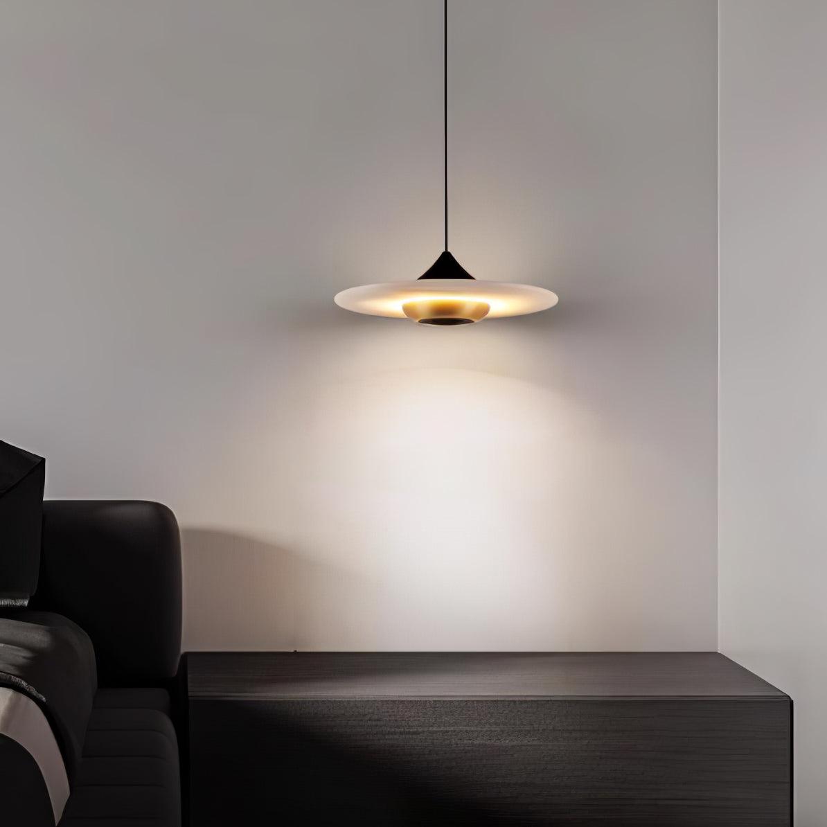Clérachic white disc pendant hangs over a dark wood nightstand beside a leather headboard in a dim bedroom.