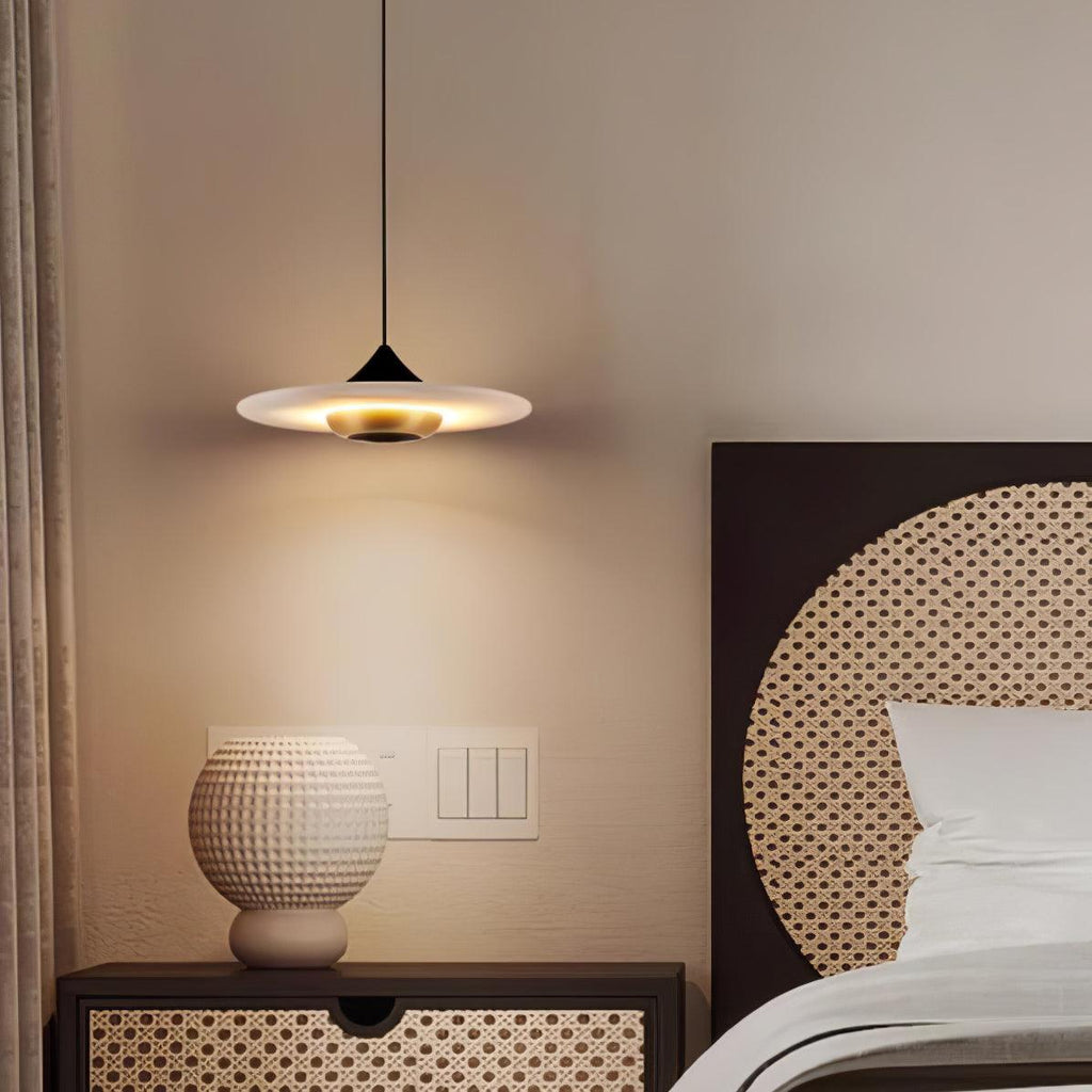 Clérachic disc pendant light hangs above a rattan-fronted nightstand holding a round white ceramic vase.