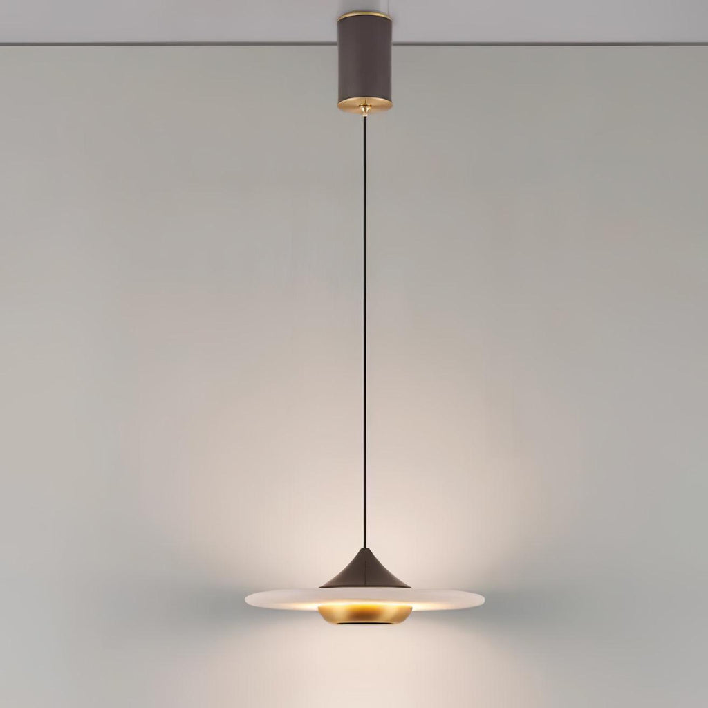Clérachic disc pendant light drops from a black cylindrical ceiling mount over a round table with a rolled magazine.