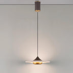 Clérachic disc pendant light drops from a black cylindrical ceiling mount over a round table with a rolled magazine.