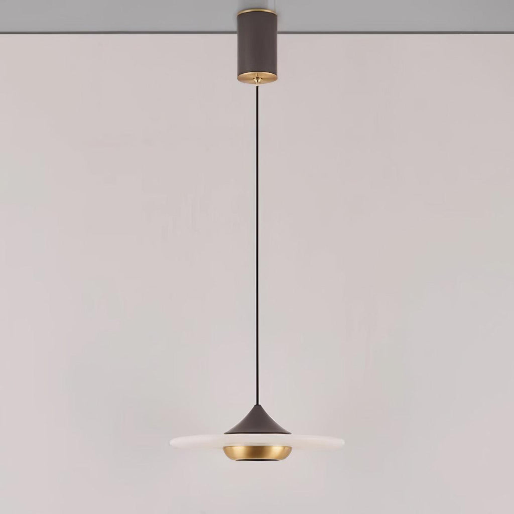 Clérachic flat disc pendant light hangs on a long black cord from its ceiling mount against a plain wall.