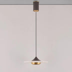 Clérachic flat disc pendant light hangs on a long black cord from its ceiling mount against a plain wall.