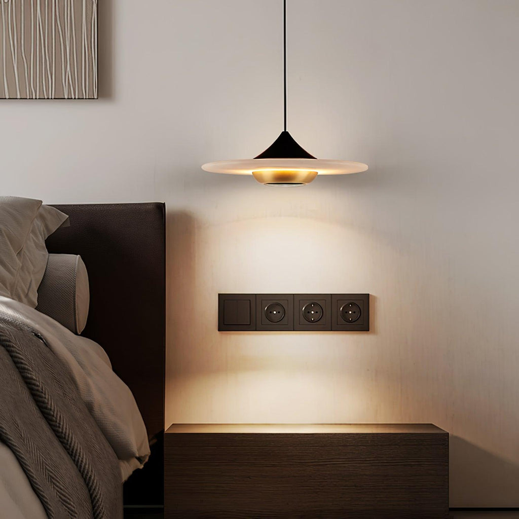 Clérachic white disc pendant glows warmly above a dark wood nightstand beside a wall-mounted socket panel.