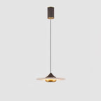 Clérachic white marble disc pendant light shown in full, from ceiling mount to glowing shade, on a plain grey backdrop.