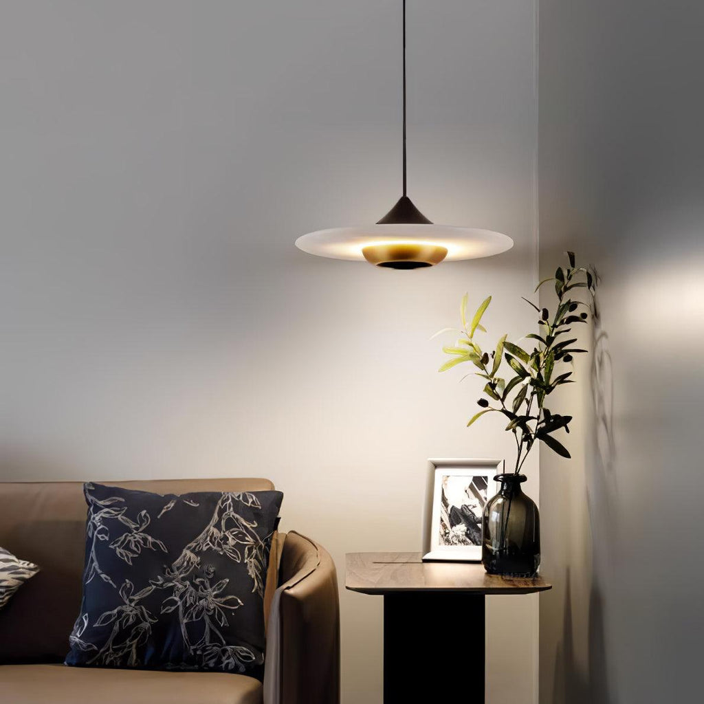 Clérachic disc pendant light hangs over a round side table with a cushion, framed photo and small potted plant.