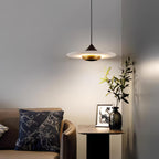 Clérachic disc pendant light hangs over a round side table with a cushion, framed photo and small potted plant.