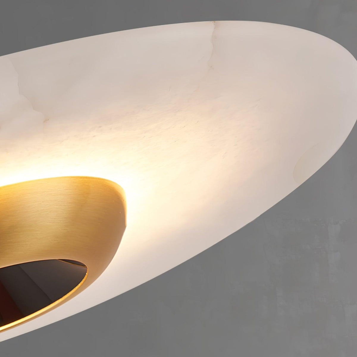 Close-up from below of a Clérachic pendant light, showing the gold trumpet fitting inside the white marble disc.