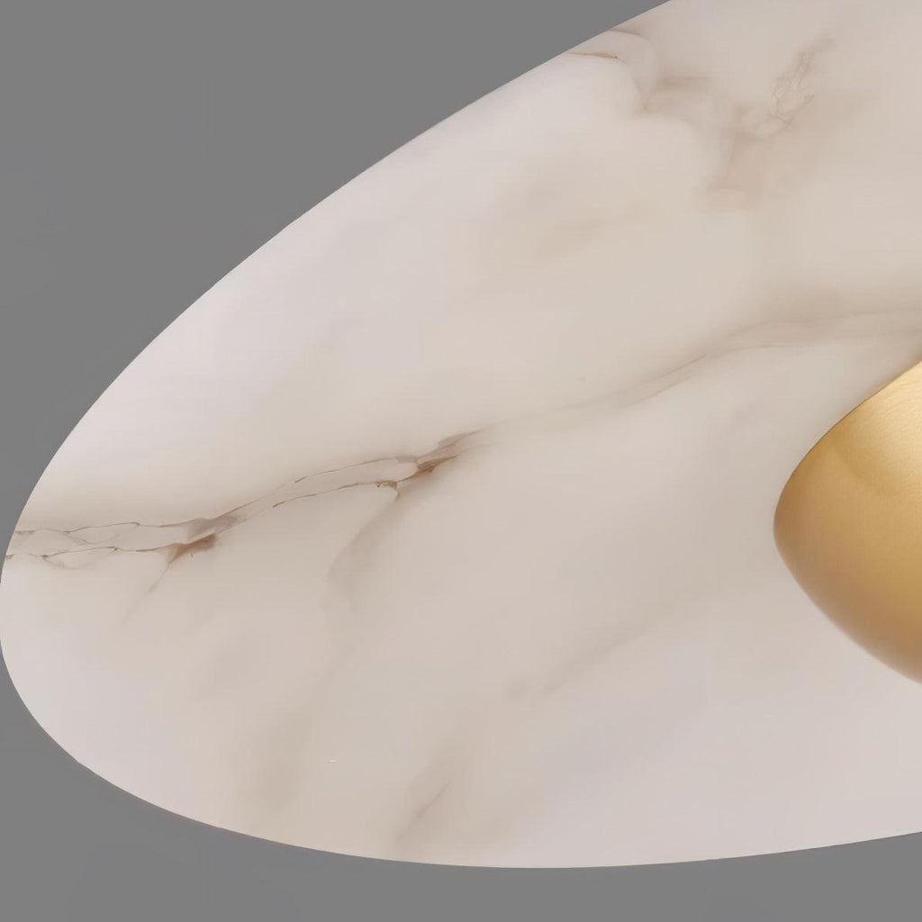 Macro close-up of the white marble disc on a Clérachic pendant light, showing its natural veining and gold underside.