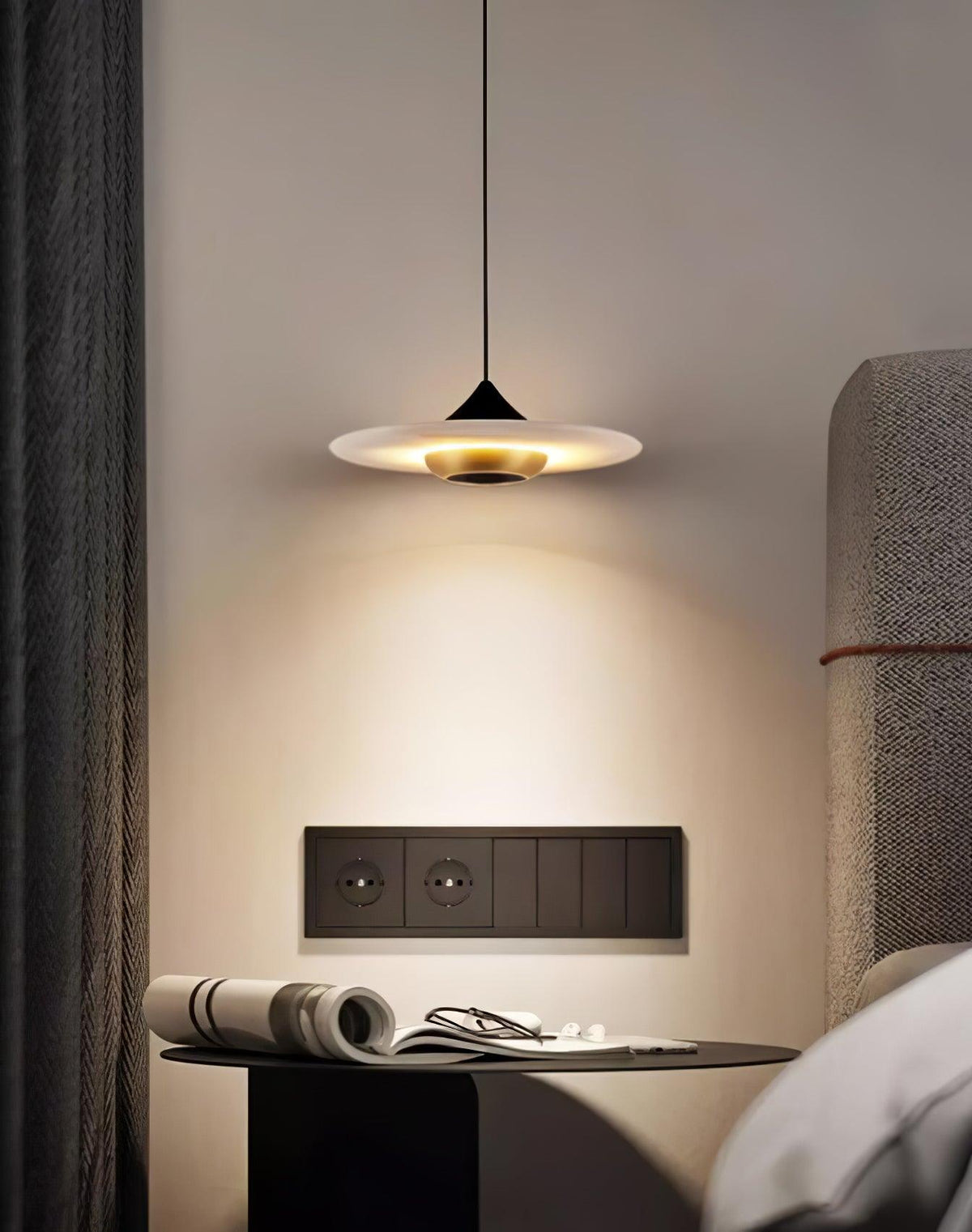 Clérachic white disc pendant lights a round side table holding a rolled magazine and reading glasses.