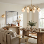 In a room with a beige sofa and a wood console table, the brass-finish chandelier from Clérachic lights a dining table nearby.