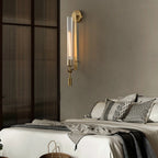 Brass sconces with ribbed glass cylinders glowing on a wall