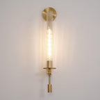 Brass wall lamp with ribbed glass cylinder glowing softly