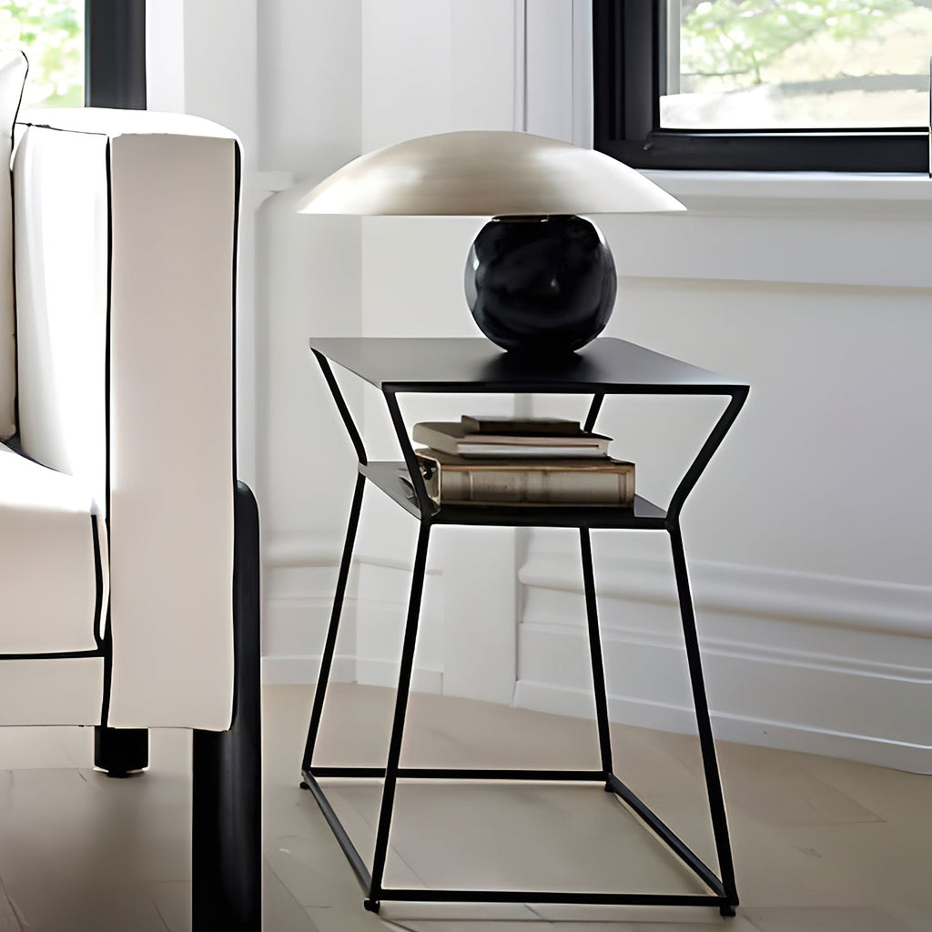 Clérachic lamp in a pewter-toned dome shade on a dark sphere base, shown on an angular black side table in a bright room.
