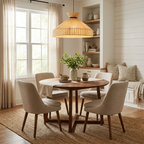 This Clérachic pendant in natural jute hangs above a round wood table with cream upholstered chairs in a window nook.