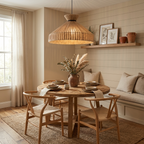 This Clérachic pendant hangs over a round table with wishbone chairs, a shelf of botanical prints on the panelled wall behind.