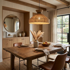 This Clérachic pendant hangs over a long wood dining table beneath exposed beams, a round mirror on the wall nearby.