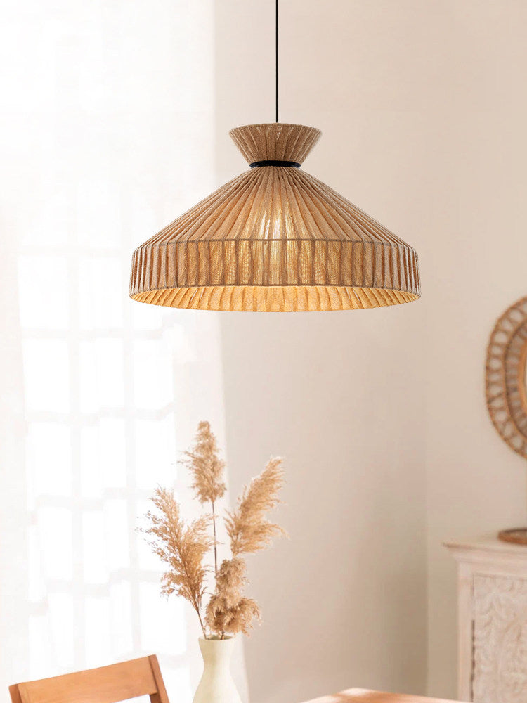 This Clérachic pendant hangs against a plain wall beside a vase of dried pampas grass and a rattan-framed mirror.